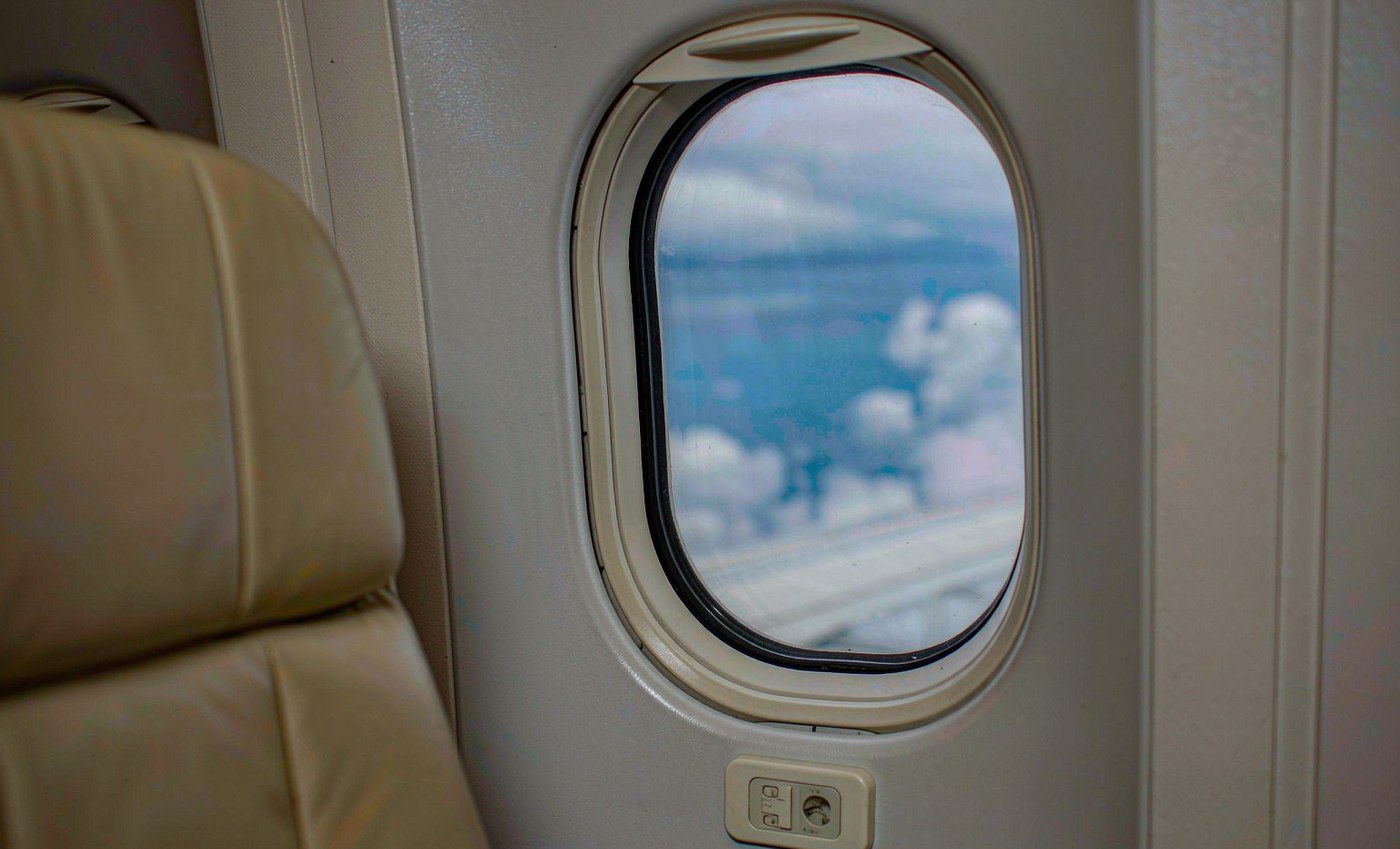 Aircraft cabin window at full clear, sky and wing visible
