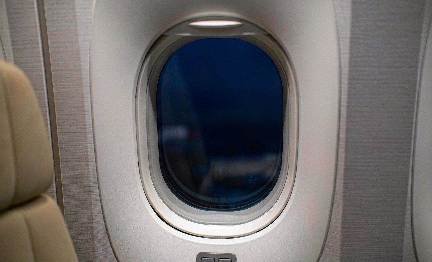 The same aircraft cabin window fully dimmed to a deep navy